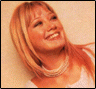 Four of a person with light brown hair and bangs, wearing a white top and pearl necklace against a beige background