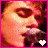 A pixelated close-up of a person singing into a microphone with a heart symbol changing from white to pink.
