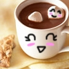 A white ceramic mug with a kawaii face drawn on it, filled with brown liquid and two marshmallows, one with a smiling face, on a light brown surface with a cookie.