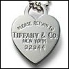 Silver heart-shaped pendant with engraved text reading 'PLEASE RETURN TO TIFFANY & CO. NEW YORK 32844' on a white background.