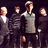 Pixelated group of figures in dark clothing with light collars, standing against a black background; text reads 'The Cinematics' at bottom right.