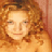 Pixelated static image of a person with curly red hair and light skin tone, cropped to show upper body against warm-toned background.