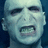 Pixelated image of a pale face with dark eyes and open mouth on left, blue background with pixelated text on right.