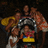 Pixelated image of multiple figures in dynamic poses with metallic and colorful elements against dark background.