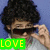 Pixelated image of a person with dark curly hair holding an object near their face, green text reading LOVE at bottom left.
