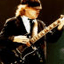 Pixelated static image of a person in formal attire playing an electric guitar with visible motion blur on the instrument and hands.