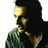 Pixelated profile view of a person with dark hair wearing a green patterned shirt against white background.