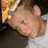 Pixelated close-up of a person's face with light skin tone, visible ear, and dark hair against a blurred background.