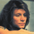 Pixelated close-up of a person with dark shoulder-length hair against a muted background with warm and cool tones.