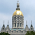Pixelated image of a large domed building with a golden dome, stone facade, and smaller spires under a light blue sky.