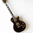 Black electric guitar with light brown accents on white background, angled diagonally from top-left to bottom-right.