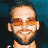Pixelated image of a person with short dark hair and orange-tinted glasses against a blue background, next to green text reading 'Original Icons .com' on a solid green backdrop.