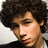 A pixelated image of a person with curly hair on the left, next to bright pink background with orange text reading 'still in love with you!' on the right.