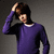 A person in a purple long-sleeve shirt with white collar stands against gray background, hand on head, mouth open.