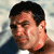 Static pixelated image of a person's face with dark hair and light skin, wearing a blue top against a blurred background.
