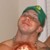 Pixelated static image of a person with green hair, closed eyes, and a neutral expression against a light background.