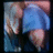 A pixelated figure in blue shorts and a gray top, with visible hands and legs against a dark background.