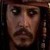 Pixelated close-up of a person's face with dark hair, wearing a dark hat and dark clothing against a dark background.
