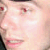 Pixelated close-up of a person's face showing eyes, nose, mouth, and partial hair with light skin tones and red accents on eyelids and lips.