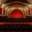 A pixelated image of a theater facade with a glowing red marquee and ornate architectural details.