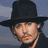A static image of a person wearing a black wide-brimmed hat, with visible facial features and dark clothing against a muted background.