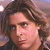 Static pixelated image of a person with brown hair and light skin, cropped to show the head and upper shoulders against a blurred background.