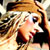 Static 50x50 pixel icon showing a close-up of a person with long light brown hair wearing dark clothing, rendered in low-resolution pixel art style with warm color tones and visible dithering.