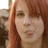 A static pixelated image shows a person with long reddish-brown hair, light skin tone, and visible facial features including eyes, nose, mouth, and eyebrows.