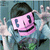 Pixelated character with pink mask, black hair, and blue shirt extends both hands forward in a reaching pose against a blue background.