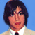 Static pixelated image of a person with dark hair wearing a light-colored shirt and dark tie against solid blue background.