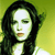 Pixelated portrait of a person with long dark hair against a green-yellow gradient background, wearing a light-colored top.