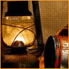 A vintage oil lamp with glowing light and metal frame, positioned next to a partially visible cylindrical object with red and silver details.