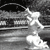 Black-and-white pixelated image showing a figure in motion with blurred background elements suggesting speed or movement.