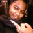 Pixelated close-up of a person with light skin and brown hair, wearing dark clothing against a black background.