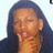 Pixelated static image of a person with long dark hair, closed eyes, and hand near mouth against light background.