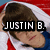 A person with brown hair and a white towel draped over their head wears a blue shirt against red-and-white striped background; text "JUSTIN B." appears in black block letters.