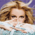 Pixelated image of a person with light brown hair lying in water, wearing a white top against a purple background.