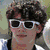 Six distinct poses of a young man with curly brown hair in various outfits and settings, including sunglasses, a tank top, and a sports jersey.