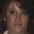 A static digital image with green text on a black background, featuring a small portrait of a woman with brown hair and a white top.