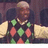 A person in a diamond-patterned argyle sweater with green and red diamonds on black, beige sleeves, and a white collar. The right side shows text "OH Evon!" in pixelated font.