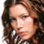 Pixelated close-up of a person with long brown hair wearing a checkered shirt and white earrings.