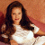 A pixelated image of a woman with long dark hair in a white dress, seated against a reddish-brown background next to green text reading 'Original Icons .com'.