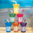 Stack of colorful cartoon drink glasses with straws on a beach background, right side shows pixelated text.