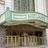 Static image of a building facade with columns and a sign, rendered in low-resolution pixels.