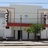 Static pixelated image of a building with a red roof, dark door, and green tree in front, set against a light sky.