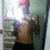 A shirtless person with a bare torso and black shorts stands in a room with a green wall and a window, holding a camera or phone to take a photo.