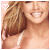 A pixelated image of a smiling woman with long brown hair wearing a white strap top, featuring a small heart symbol in the corner.