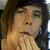 A person with long dark hair appears in two , first resting a hand near their mouth then opening the mouth wide against an indoor background
