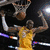 A basketball player in a yellow jersey dunks while another player in white with number 24 stands nearby.