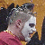 A pixelated figure with white face paint and spiked hair wears a red shirt, shown in two side-by-side frames where the head turns from profile to facing forward.